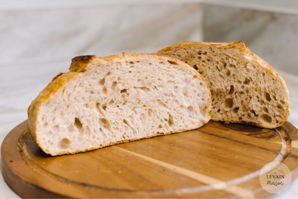 pain à la farine de blé complet de à la farine pour pain, coupé en deux et ouvert posé sur une planche en bois